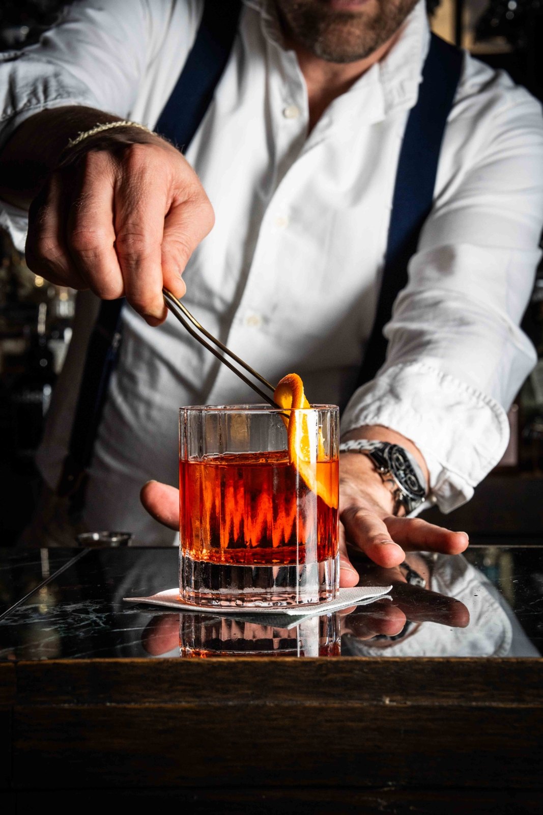 Bartender werkt een cocktail af met een sinaasappelschil