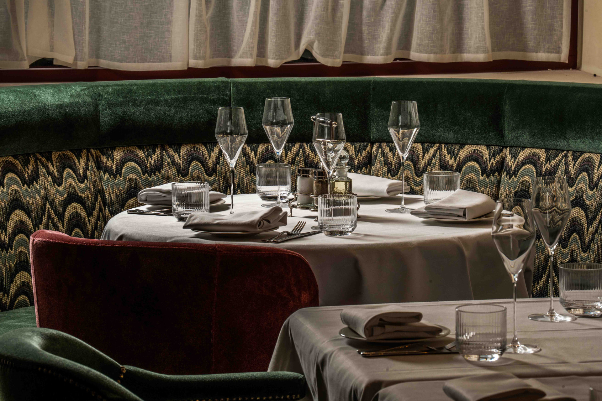 Sfeervol restaurantinterieur met gedekte tafels en groen fluweel